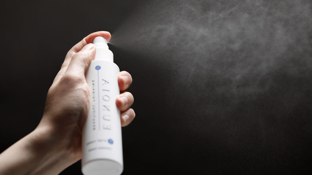 Hand holding a white spray bottle labeled 'Eunoia' against a dark background